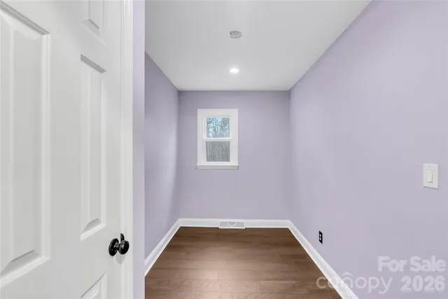 a view of a hallway with wooden floor and a bathroom