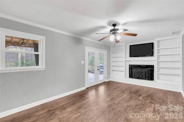 a view of a livingroom with a fireplace a ceiling fan and wooden floor