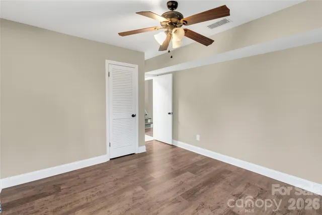 an empty room with wooden floor ceiling fan and window