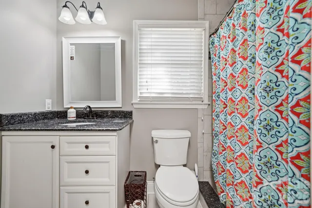 a bathroom with a granite countertop toilet sink and mirror