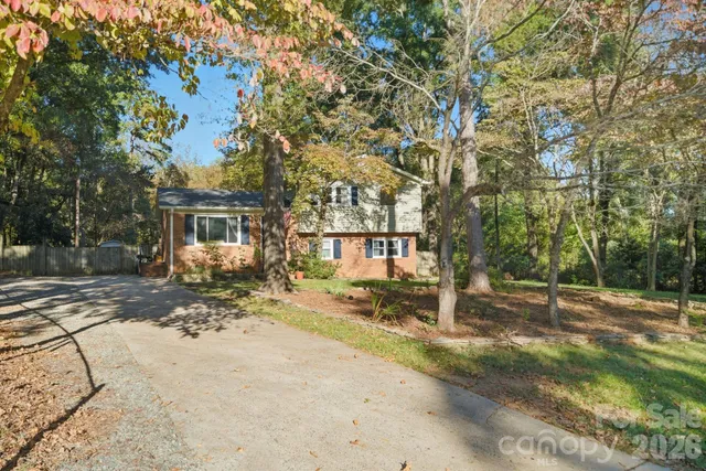a view of a house with large tree and wooden fence