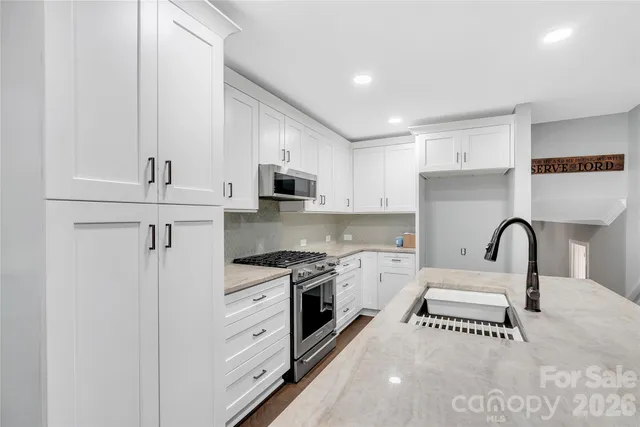 a kitchen with white cabinets stainless steel appliances and a sink