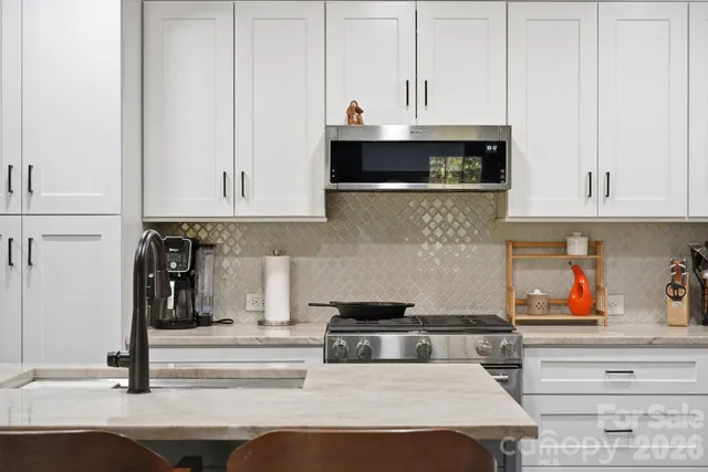 a kitchen with stainless steel appliances granite countertop a stove and white cabinets
