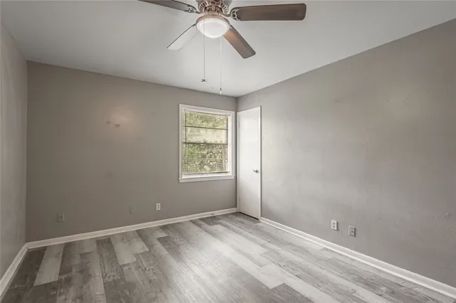 an empty room with a window and a fan