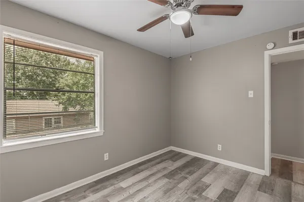 a view of empty room with window and ceiling fan