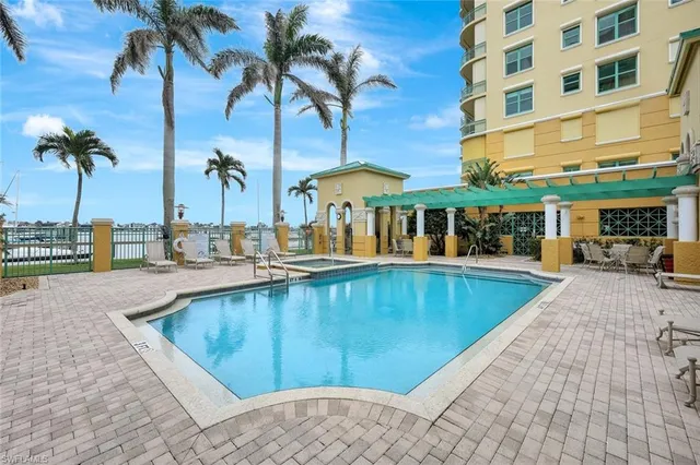 a view of a swimming pool with a lawn chairs under palm trees