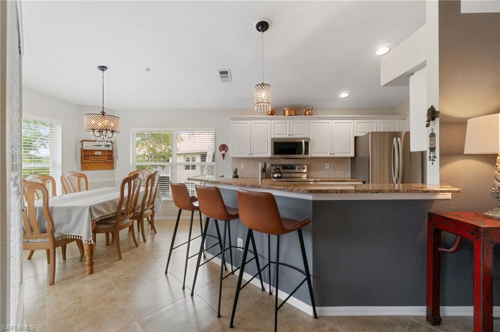 359 Dover Place, Unit E204 Naples, FL 34104 - Photo 12 of 49 a kitchen with stainless steel appliances kitchen island granite countertop a table chairs sink and cabinets
