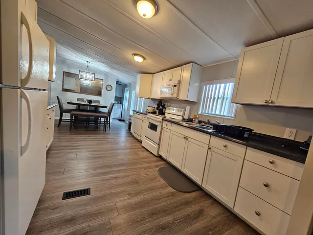 a kitchen with stainless steel appliances granite countertop a stove a sink dishwasher and a refrigerator with wooden floor