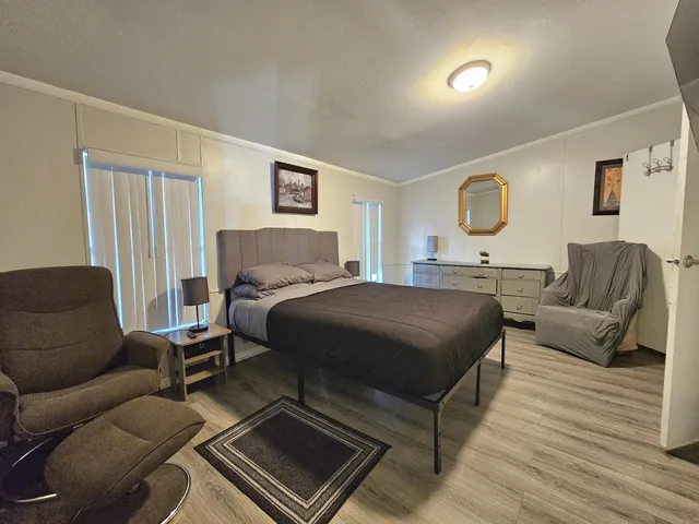 a bedroom with a bed a couch and potted plant on the dresser