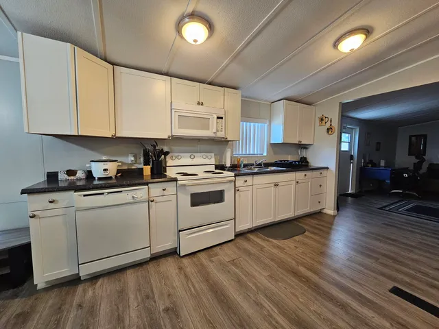 a kitchen with stainless steel appliances white cabinets a sink a stove a refrigerator and cabinets