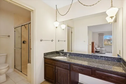 a bathroom with a granite countertop sink a toilet and a mirror