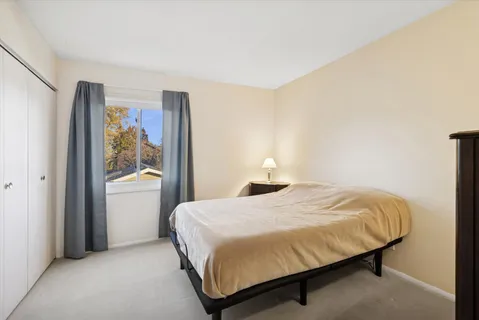 a bedroom with a bed lamp and a large window