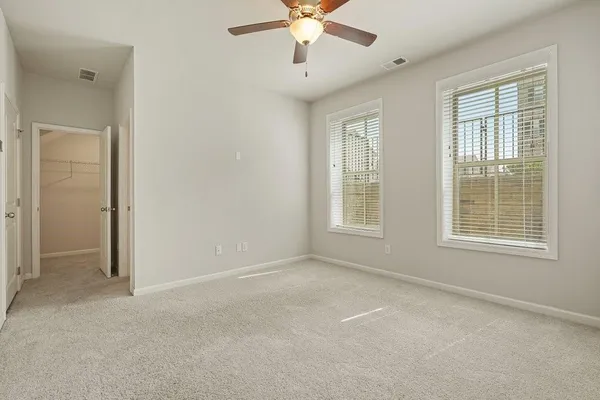 an empty room with chandelier fan and windows