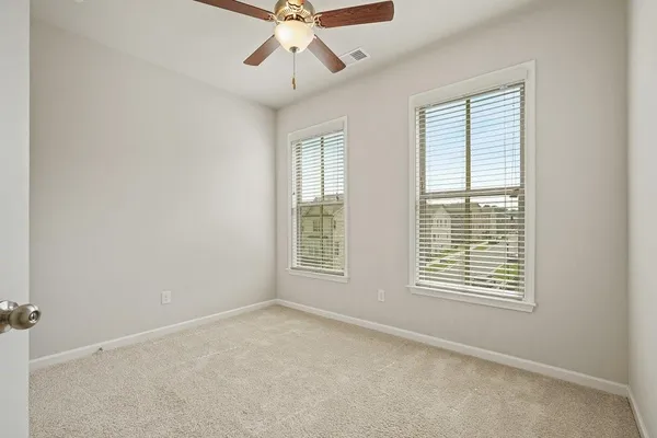 an empty room with windows and fan
