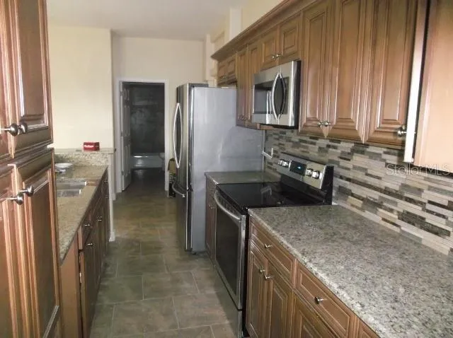 a kitchen with granite countertop a sink stove and refrigerator