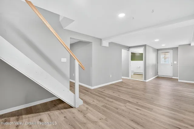 a view of an empty room with wooden floor and stairs