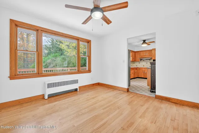 a view of an empty room with a window and wooden floor