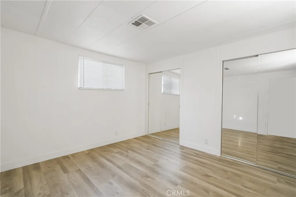 5580 Moreno Street, Unit 87 Montclair, CA 91763 - Photo 7 of 19 an empty room with wooden floor and windows