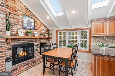 a kitchen with stainless steel appliances granite countertop a stove top oven a sink dishwasher a dining table and chairs with wooden floor