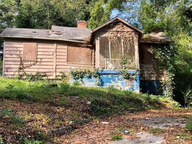a view of a house with a small yard and large tree