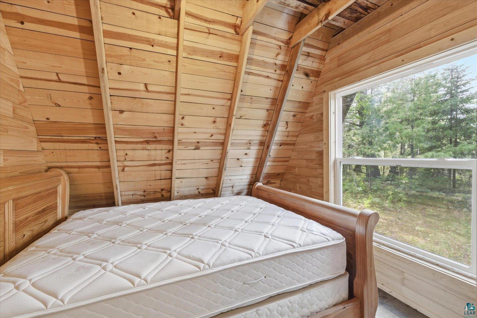 5298 Long Island Tower, MN 55790 - Photo 7 of 31 Wood-paneled interior featuring exposed ceiling beams, a large window, and a wood-frame bed