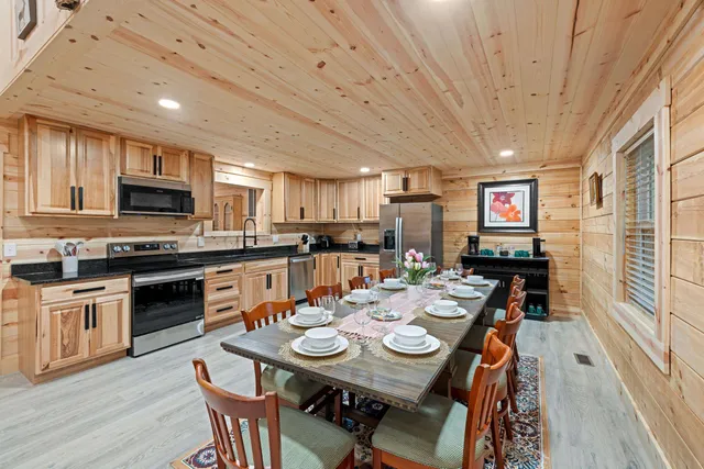 a open dining room with stainless steel appliances kitchen island granite countertop a table chairs and a refrigerator