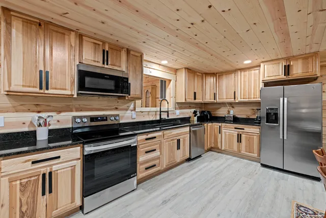 a kitchen with stainless steel appliances granite countertop a stove a sink dishwasher a refrigerator and a microwave oven with wooden floor