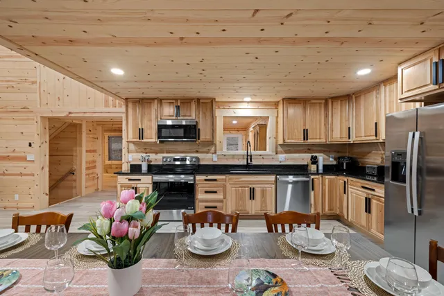 a kitchen with stainless steel appliances kitchen island granite countertop a stove refrigerator and a dining table with wooden floor