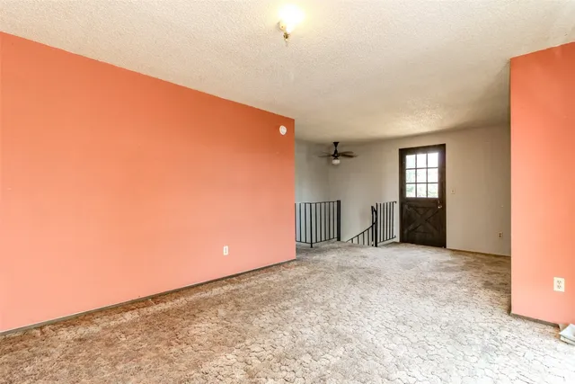 an empty room with a ceiling fan and carpet