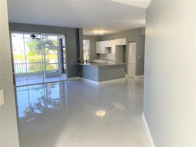 a large white kitchen with granite countertop a large window