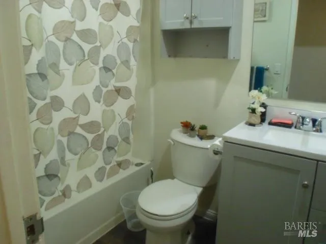 a white toilet sitting next to a bathroom sink and a shower curtain