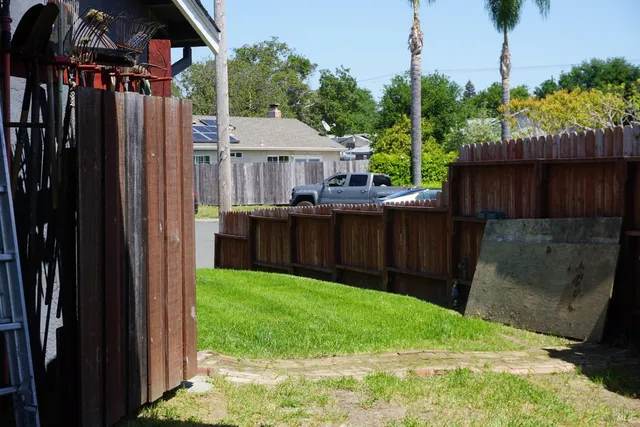 a view of backyard with potted plants and a wooden fence