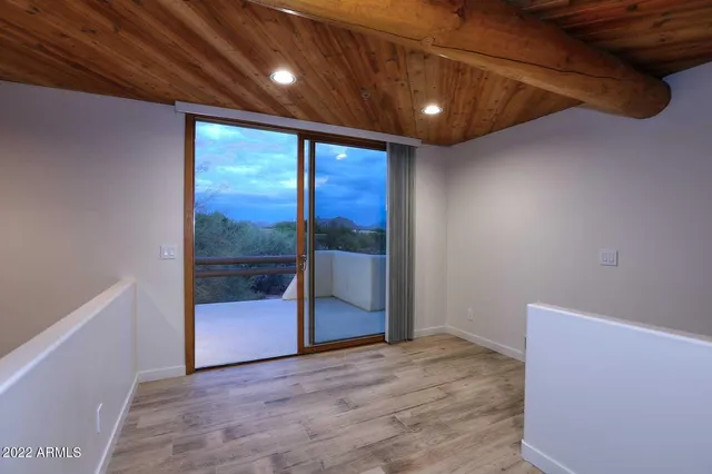 an empty room with wooden floor fan and windows