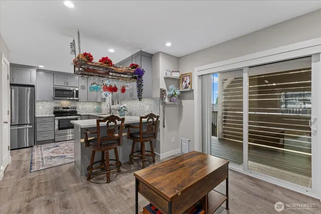 a kitchen with stainless steel appliances kitchen island granite countertop a table chairs stove and refrigerator