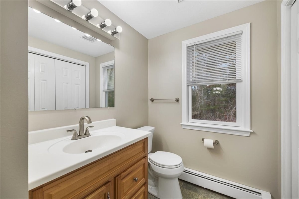 18 Heather Hill Road Bourne, MA 02532 - Photo 20 of 28 a bathroom with a toilet a sink a mirror a window and vanity