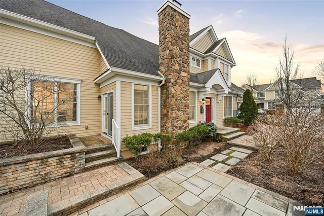 a view of a white house with a bench and potted plants