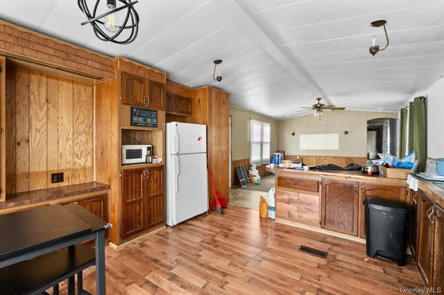 a kitchen with stainless steel appliances granite countertop a refrigerator a sink dishwasher a stove and a dining table with wooden floor