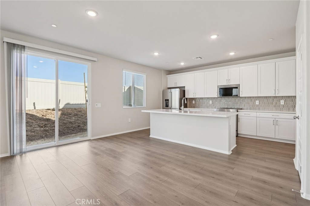 2070 Meyer Lane Redlands, CA 92374 - Photo 10 of 44 a view of kitchen with granite countertop refrigerator oven sink and white cabinets with wooden floor