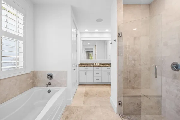 a bathroom with a tub a sink and a large mirror