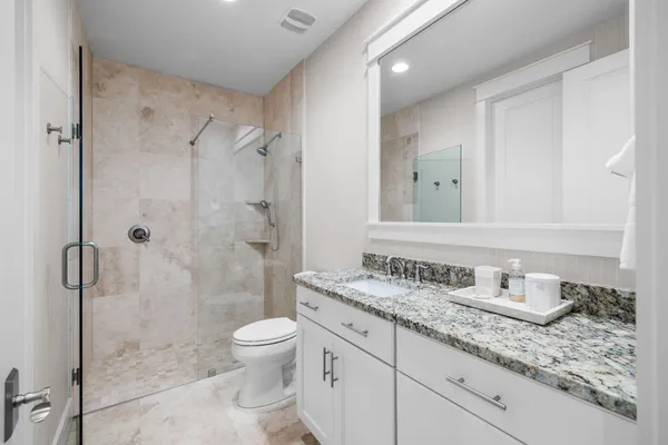 a bathroom with a granite countertop sink a toilet and a shower
