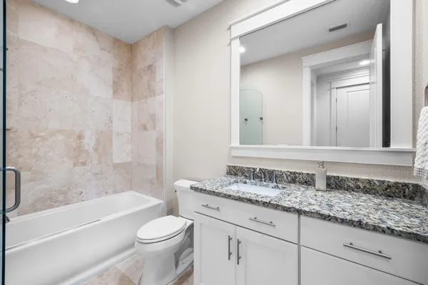 a bathroom with a granite countertop sink a toilet and bathtub