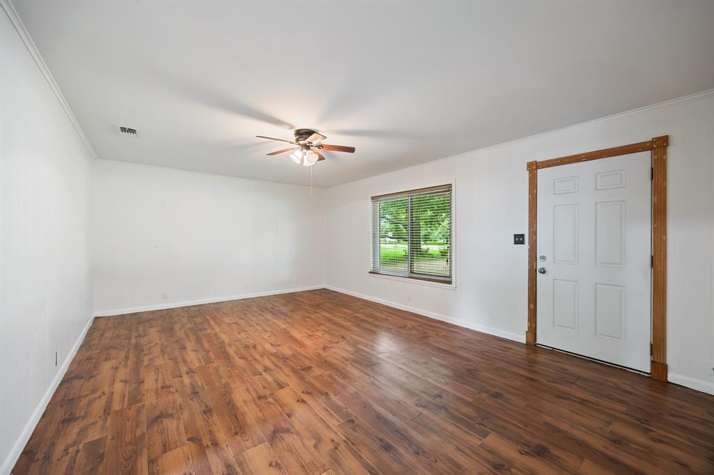 571 South 1st Street Point, TX 75472 - Photo 14 of 27 an empty room with wooden floor chandelier fan and windows