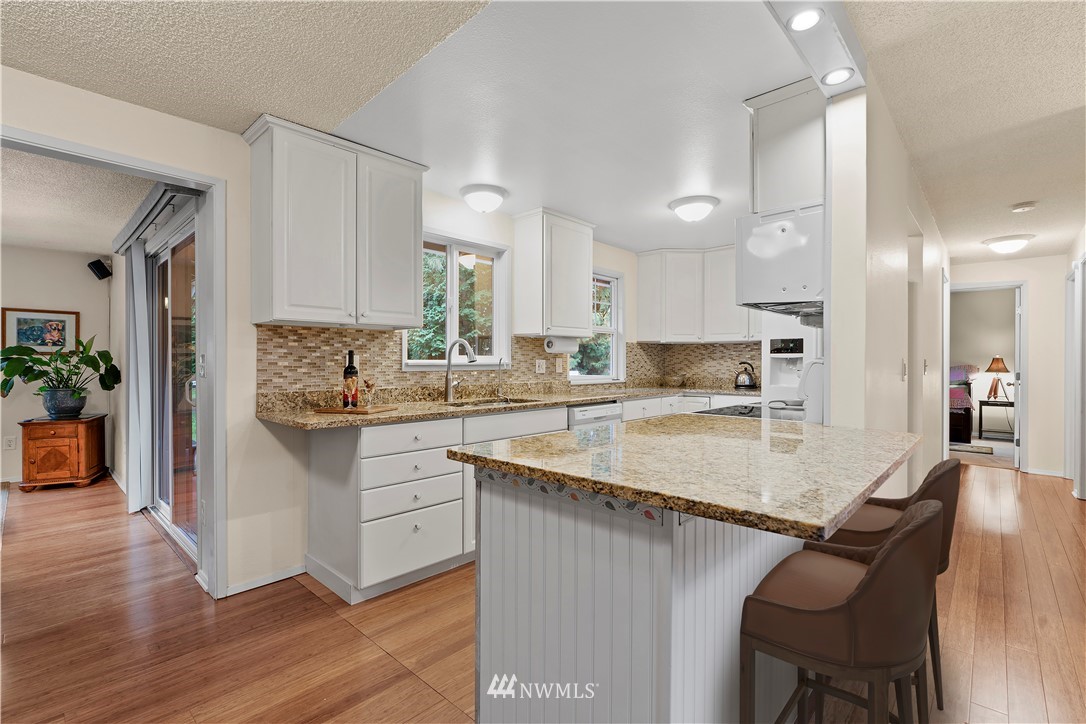 20915 West Richmond Road Bothell, WA 98021 - Photo 3 of 26 a kitchen with stainless steel appliances granite countertop a table chairs sink refrigerator and microwave