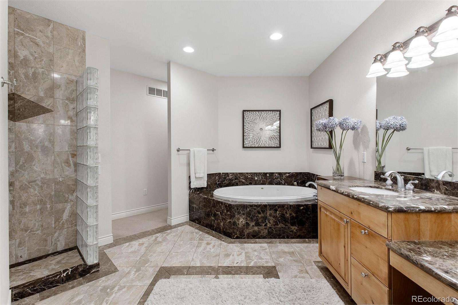 167 Monroe Street Denver, CO 80206 - Photo 20 of 39 a spacious bathroom with a granite countertop sink a toilet a mirror and shower