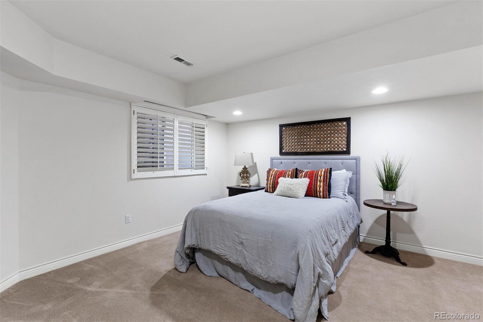 167 Monroe Street Denver, CO 80206 - Photo 27 of 39 a bedroom with a bed a mirror and a potted plant