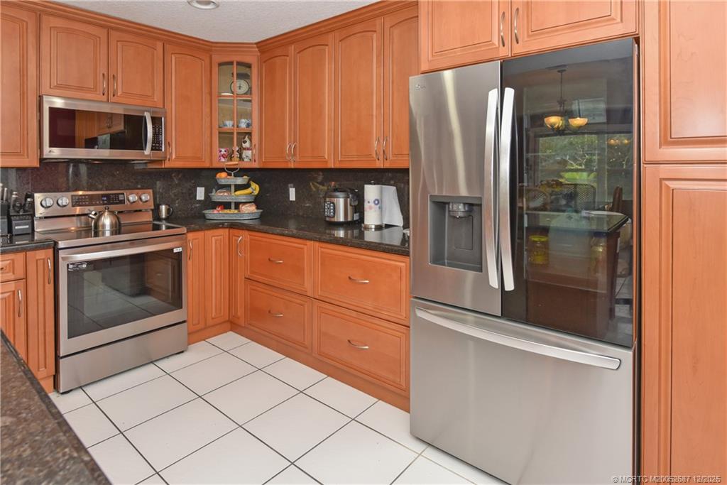 5374 Southeast Running Oak Circle Stuart, FL 34997 - Photo 6 of 38 a kitchen with stainless steel appliances granite countertop a refrigerator and a stove top oven
