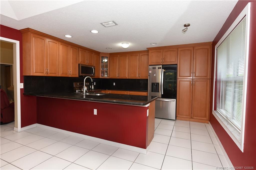 5374 Southeast Running Oak Circle Stuart, FL 34997 - Photo 7 of 38 a kitchen with stainless steel appliances granite countertop a refrigerator and a sink