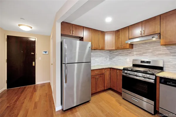 a kitchen with stainless steel appliances granite countertop a refrigerator a stove and a sink