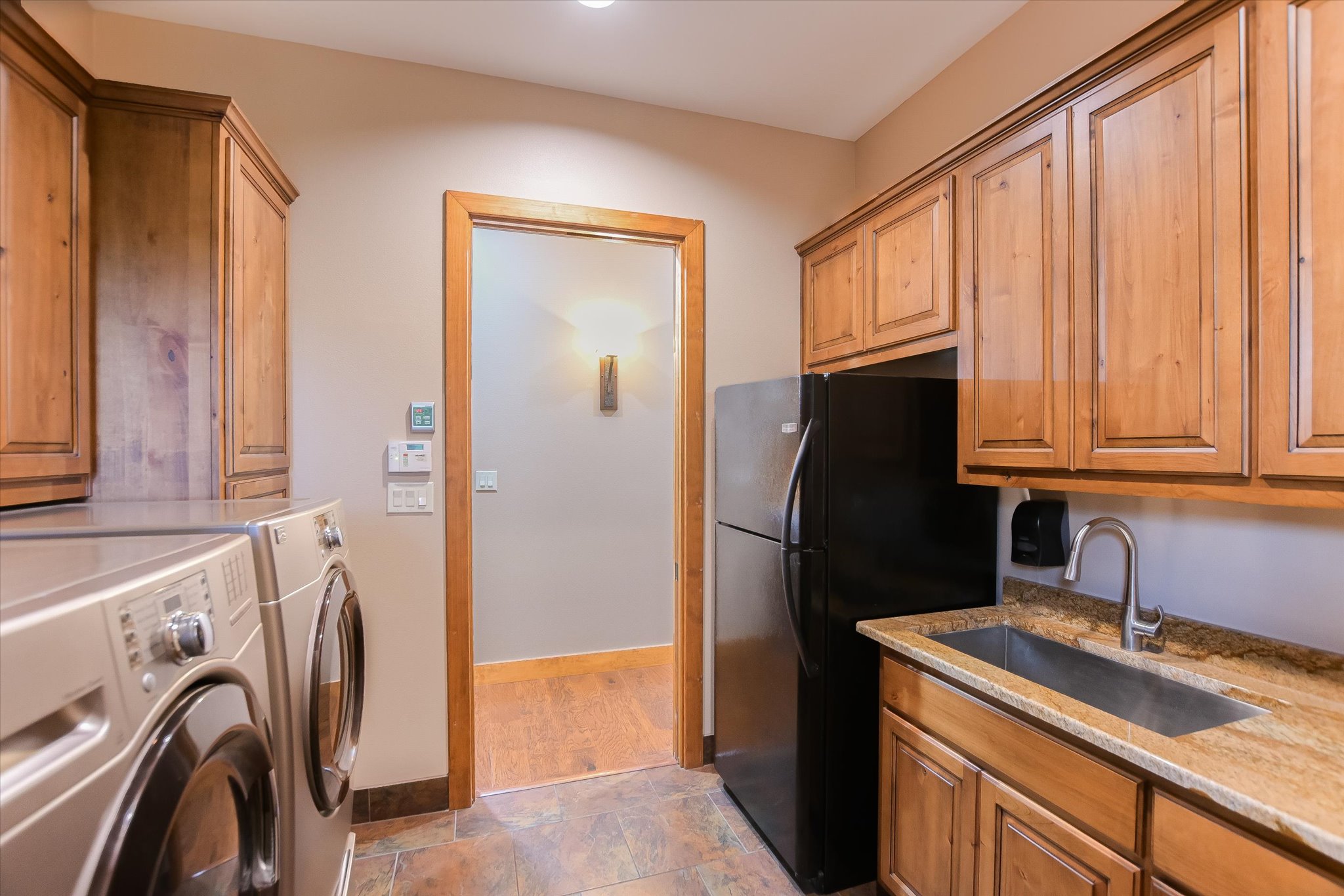409 Venture Boulevard South Point Venture, TX 78645 - Photo 22 of 37 Utility room featuring extensive wood cabinetry, granite-finish countertops, and a built-in stainless steel sink