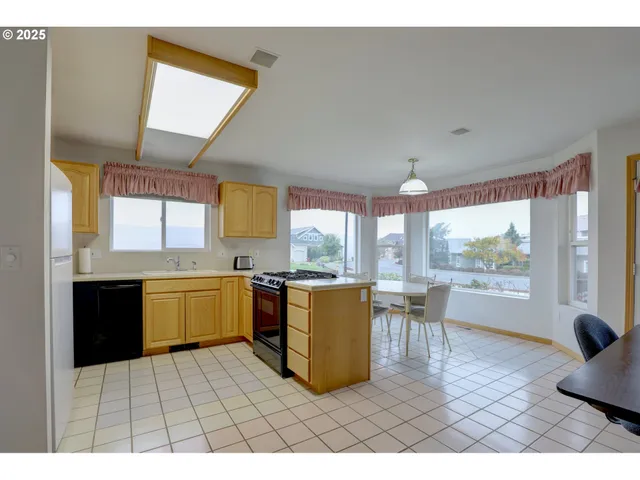 a open kitchen with granite countertop a stove top oven a sink dishwasher a dining table and chairs with wooden floor